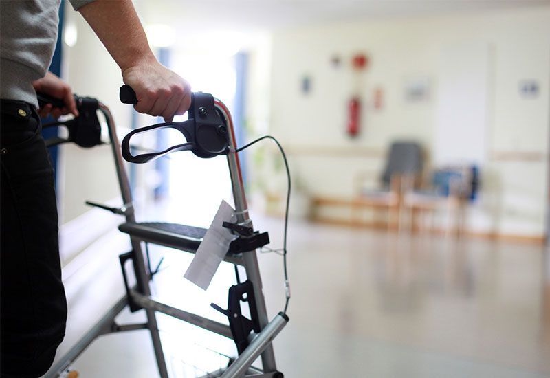 Eine Person benutzt einen Rollator in einem Krankenhausflur.