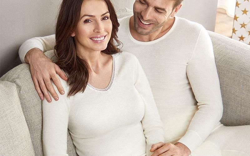 Ein Mann und eine Frau sitzen in weißer Unterwäsche auf einem Sofa.