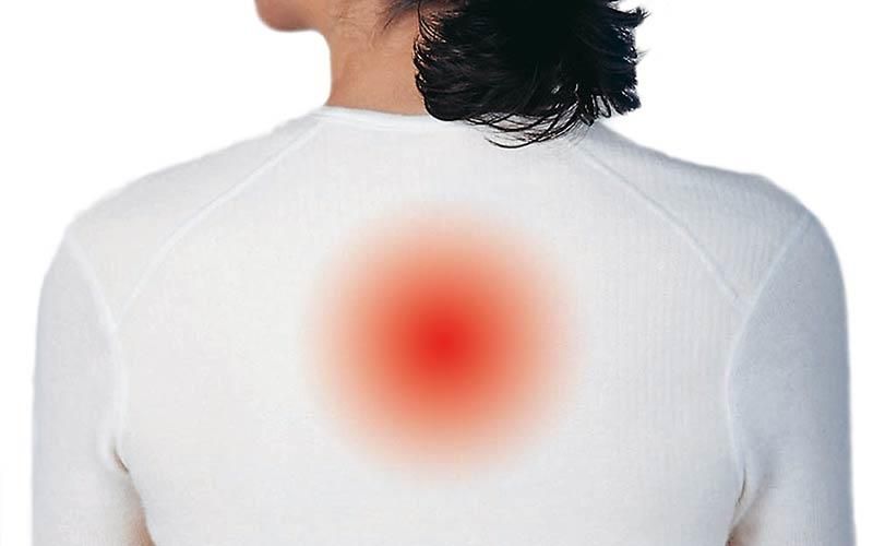 Eine Frau in einem weißen Hemd hat einen roten Fleck auf dem Rücken