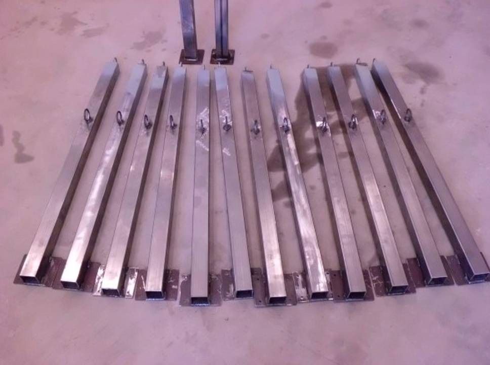 Lattialle asetetut metalliset tuulikelloraudat, joiden yläosassa on kaksi ripustustankoa.