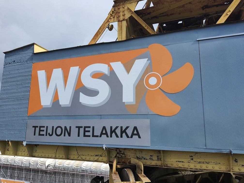 WSY-logo sinisessä rakennuksessa, jossa on kyltti, jossa lukee ”TEIJON TELAKKA”