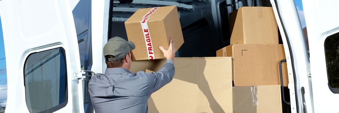 Un repartidor está cargando cajas en la parte trasera de una camioneta.