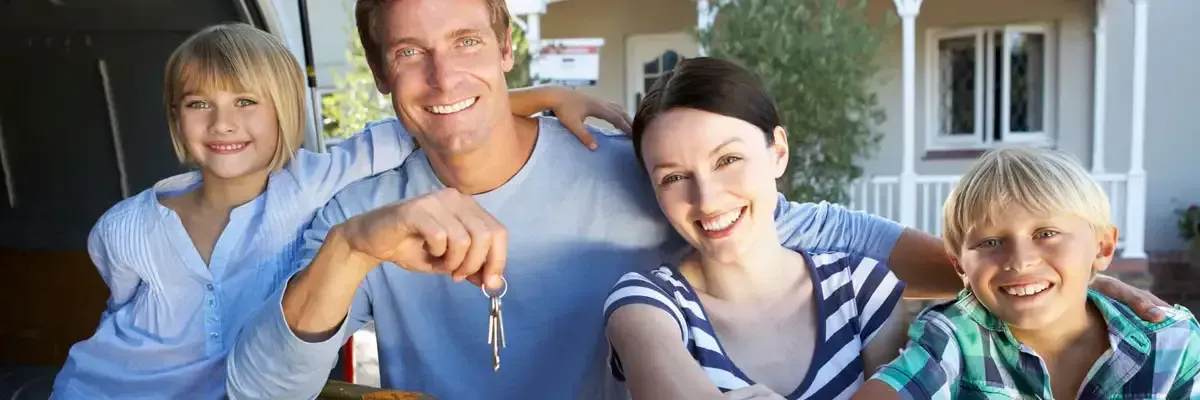 Una familia posa para una fotografía frente a su nueva casa.