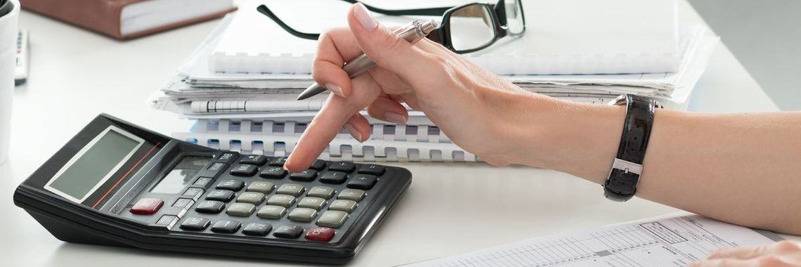 Una persona está usando una calculadora y escribiendo en un trozo de papel.