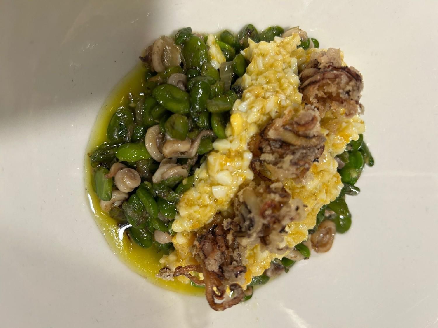 Primer plano de un plato de pasta con salsa, verduras, champiñones y queso rallado en un plato blanco.