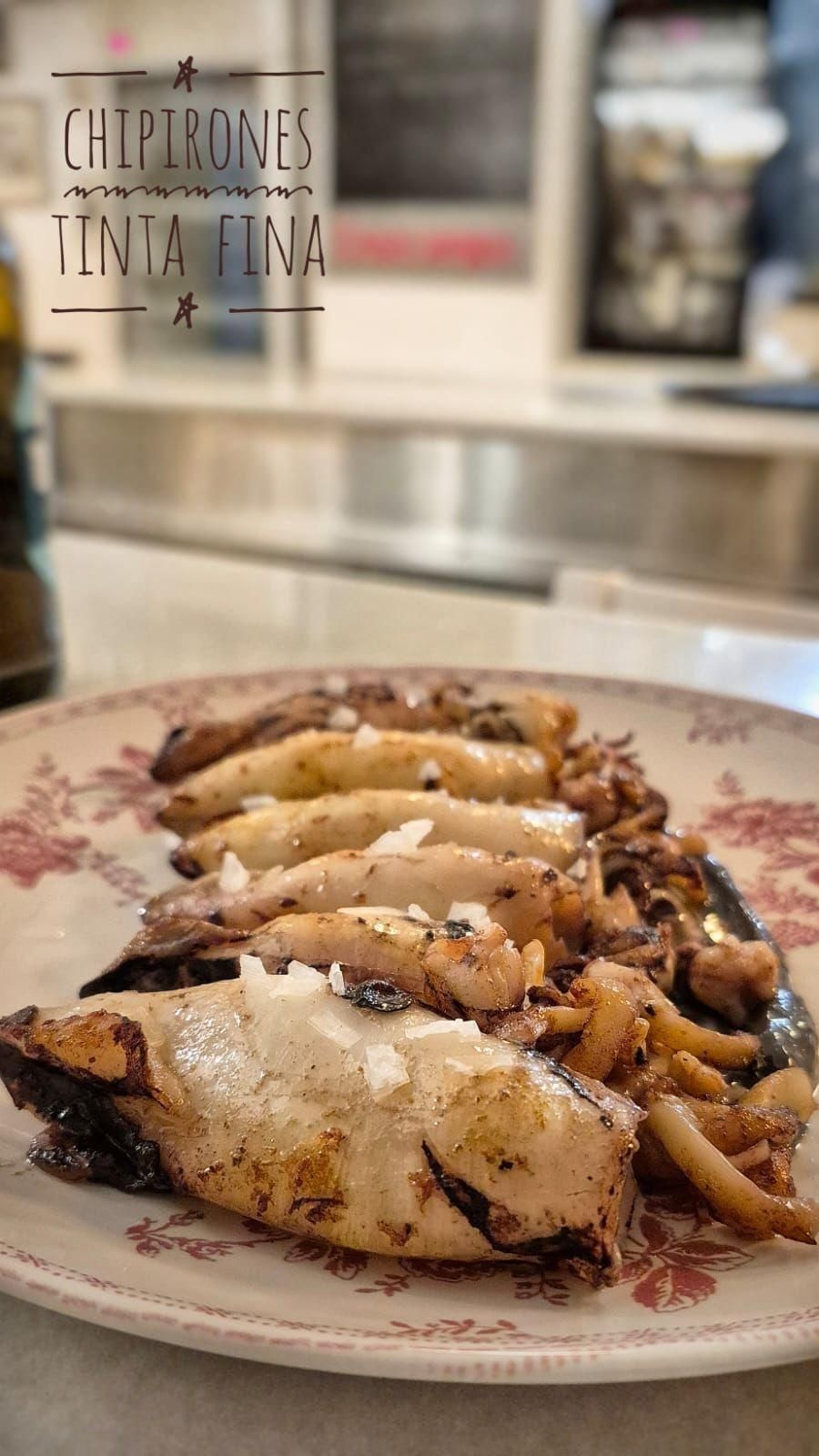 Pescado a la parrilla emplatado con patatas asadas en un plato decorado en un ambiente de restaurante.