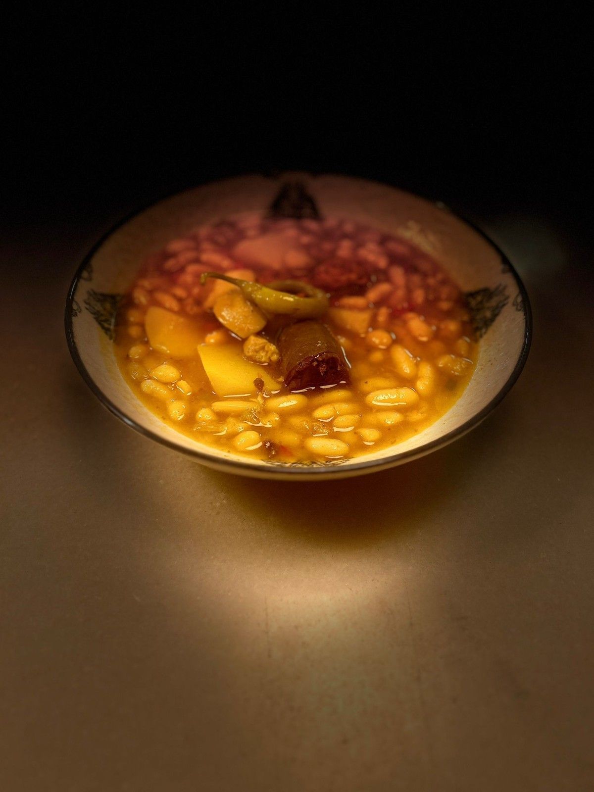 Bol de postre de frutas con salsa amarilla y bayas bajo una luz cálida.
