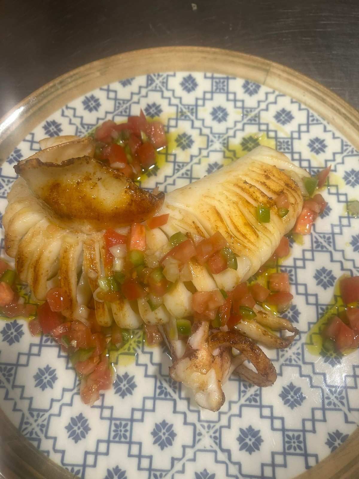 Empanadillas fritas servidas en un plato estampado, cubiertas con salsa de tomate picado y cebolla.