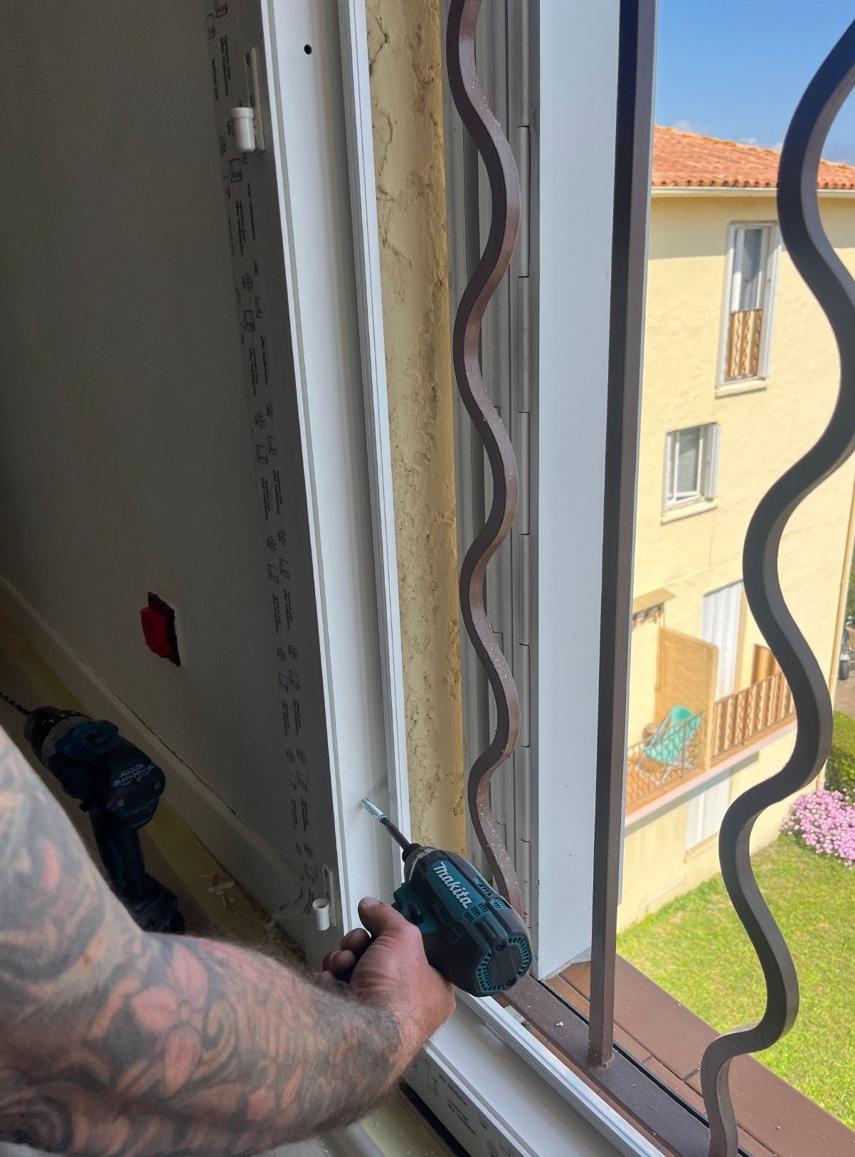 Une personne utilise une perceuse pour installer une barre de sécurité à une fenêtre.