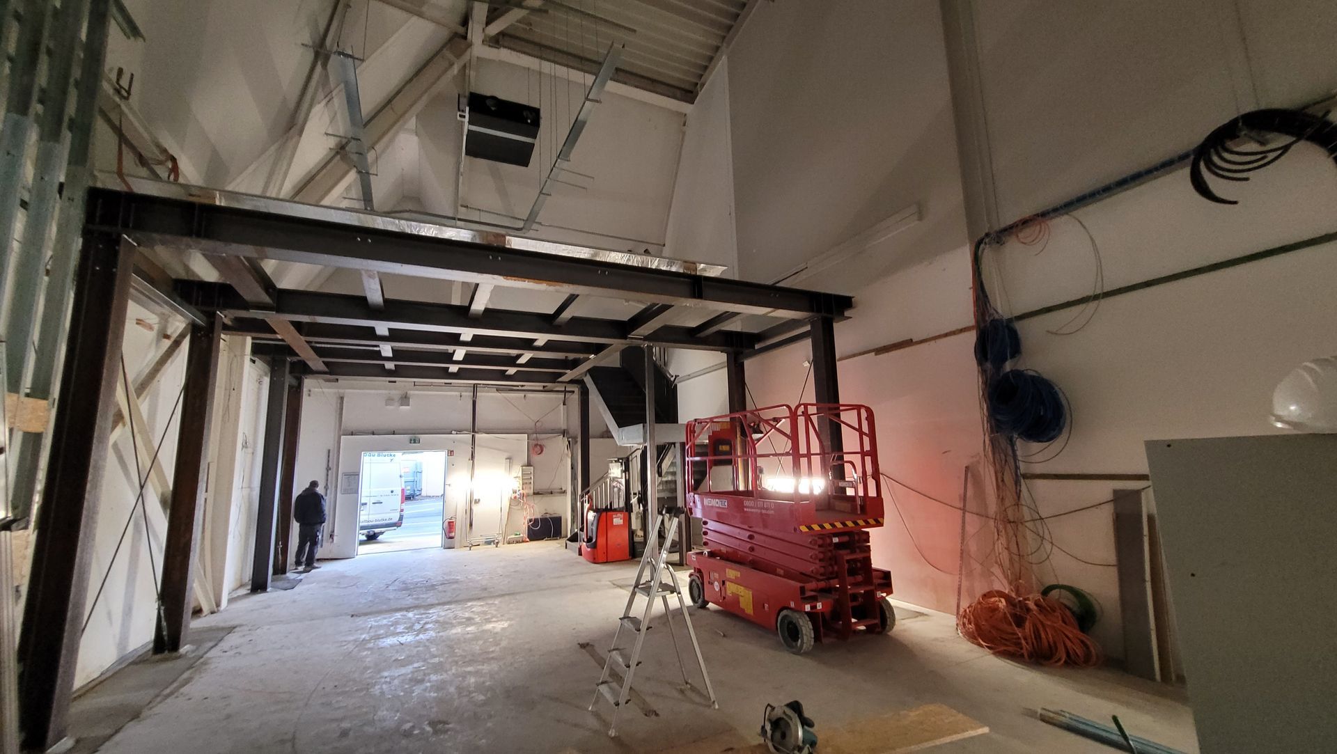 Innenbaustelle mit einem roten Aufzug und einem Metallgerüst.