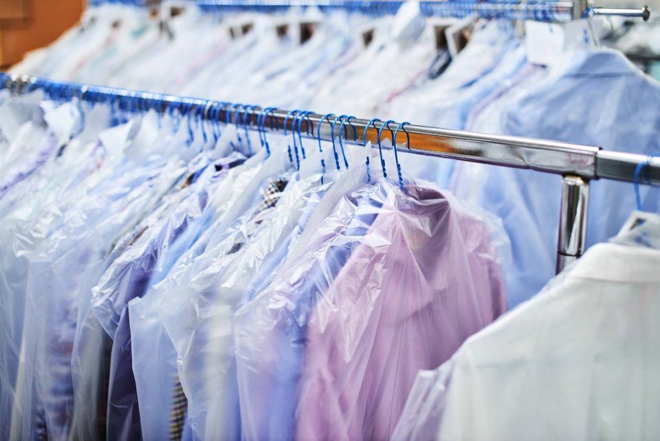 Eine Reihe von Hemden hängt auf einem Ständer in einer Reinigung.