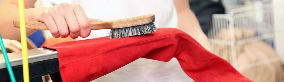 Eine Person hält eine Bürste über ein rotes Tuch.