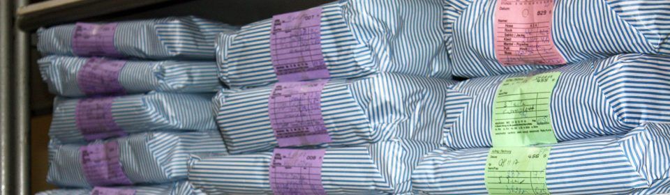 Ein Stapel gestreifter Hemden liegt übereinander auf einem Regal.