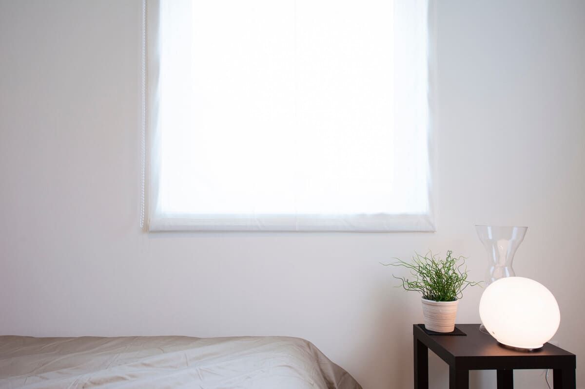 Un dormitorio con una cama, una lámpara y una ventana.