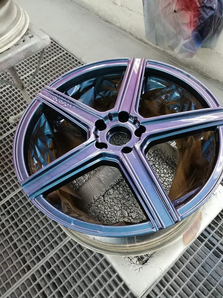 Auf einem Metallgitter sitzt eine violett-blaue Felge.