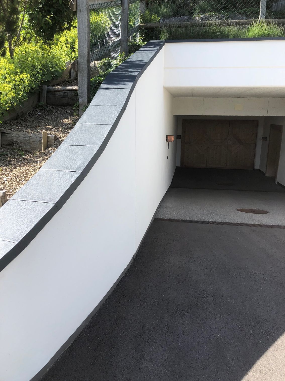 Eine weiße Wand umgibt einen Tunnel, der zu einer Garage führt