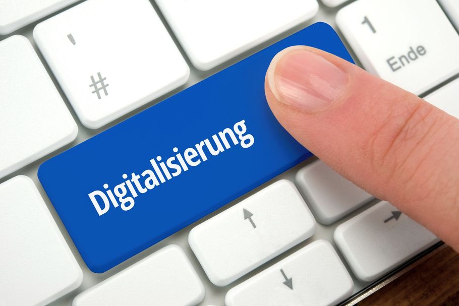 Eine Person drückt eine blaue Taste auf einer Tastatur mit der Aufschrift „Digitalisierung“