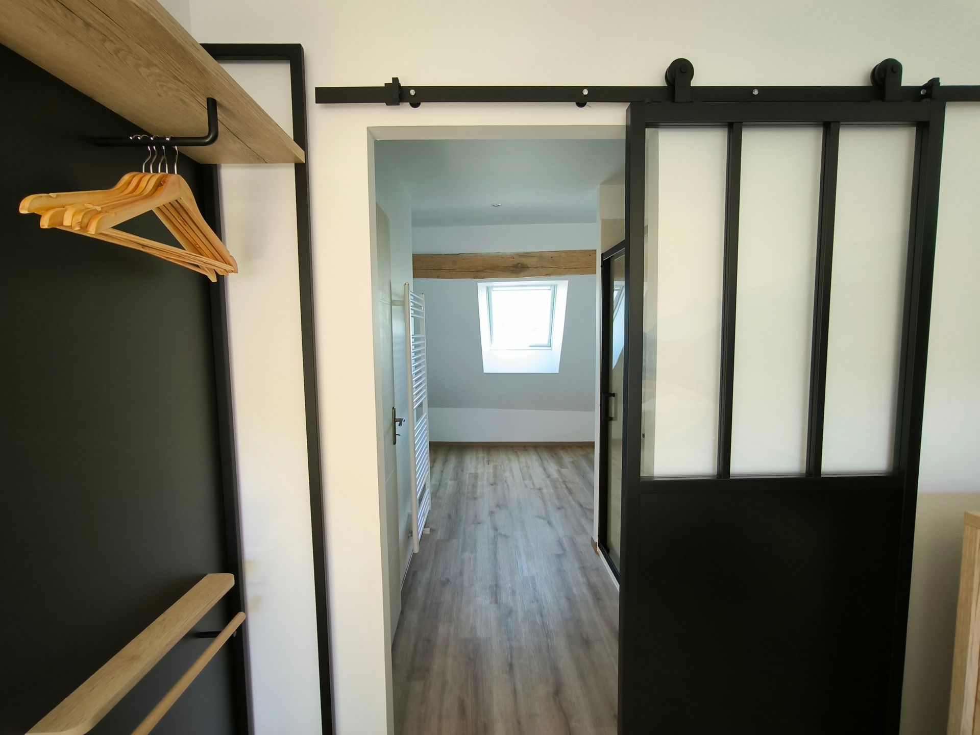 Placard vide avec portes coulissantes, parquet et vue sur un couloir lumineux avec une fenêtre.