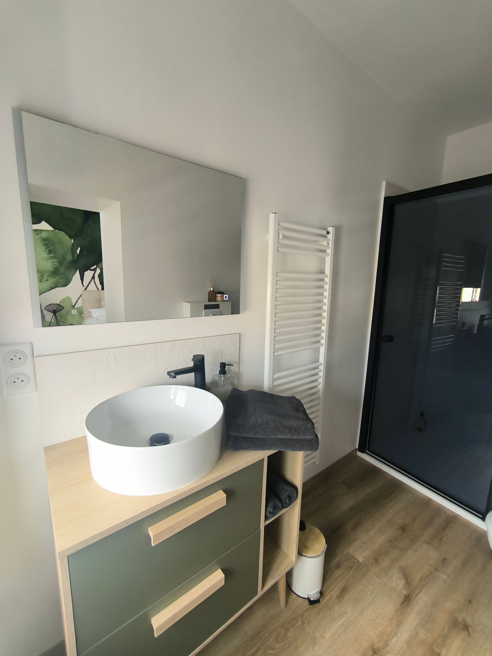 Meuble-lavabo moderne avec vasque ronde blanche, miroir, sèche-serviettes et porte de douche noire