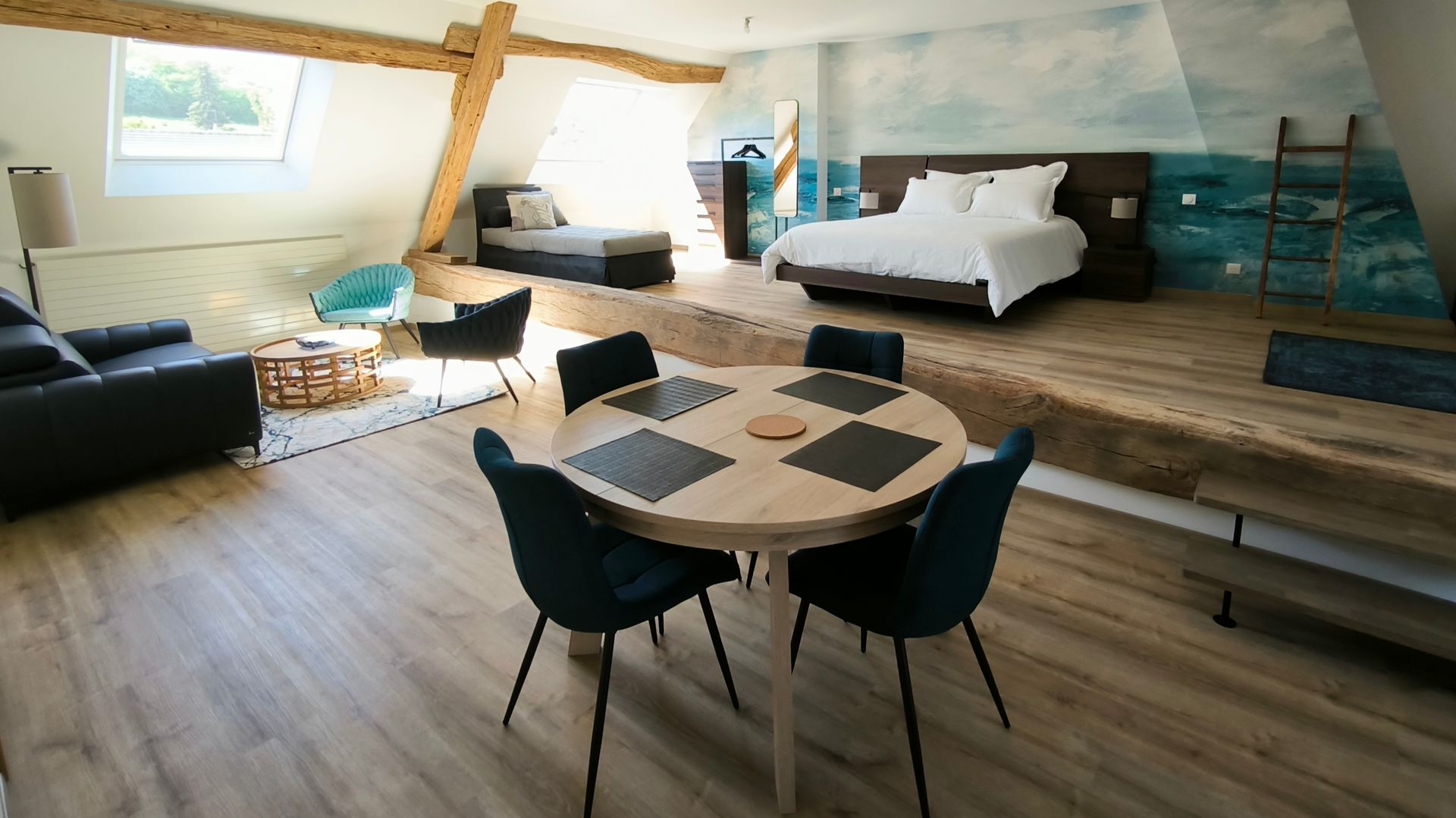 Chambre et espace de vie de style loft moderne avec lit, canapé, bureau et table à manger ronde
