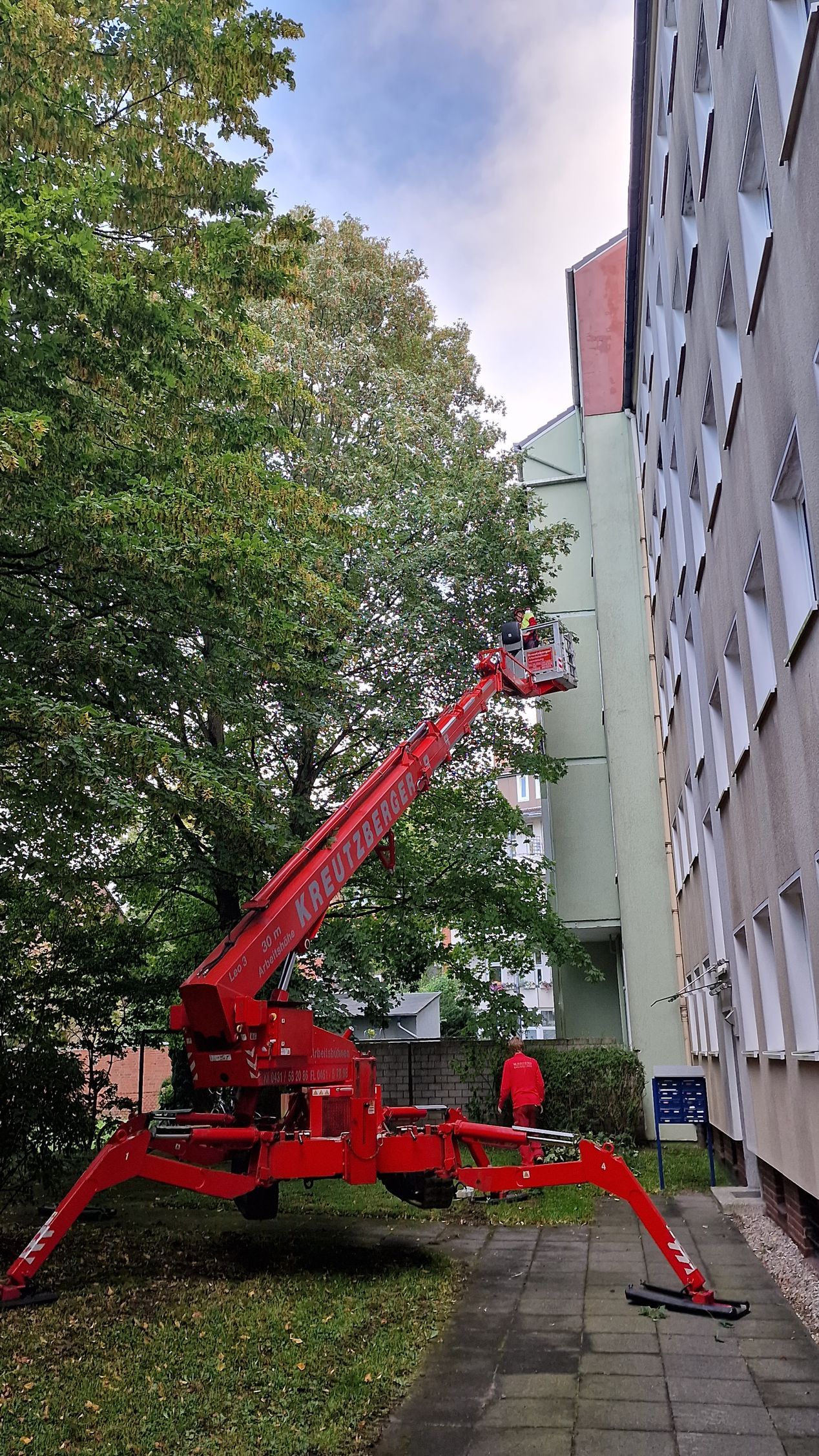 Ein roter Kran steht auf einem Bürgersteig vor einem Gebäude.