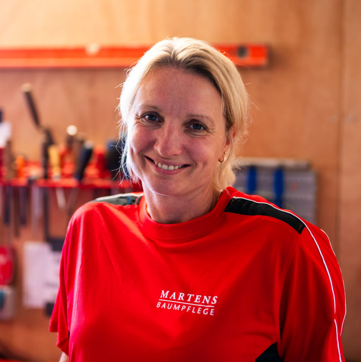 Eine Frau trägt ein rotes T-Shirt mit der Aufschrift „Martens Baumpflege“
