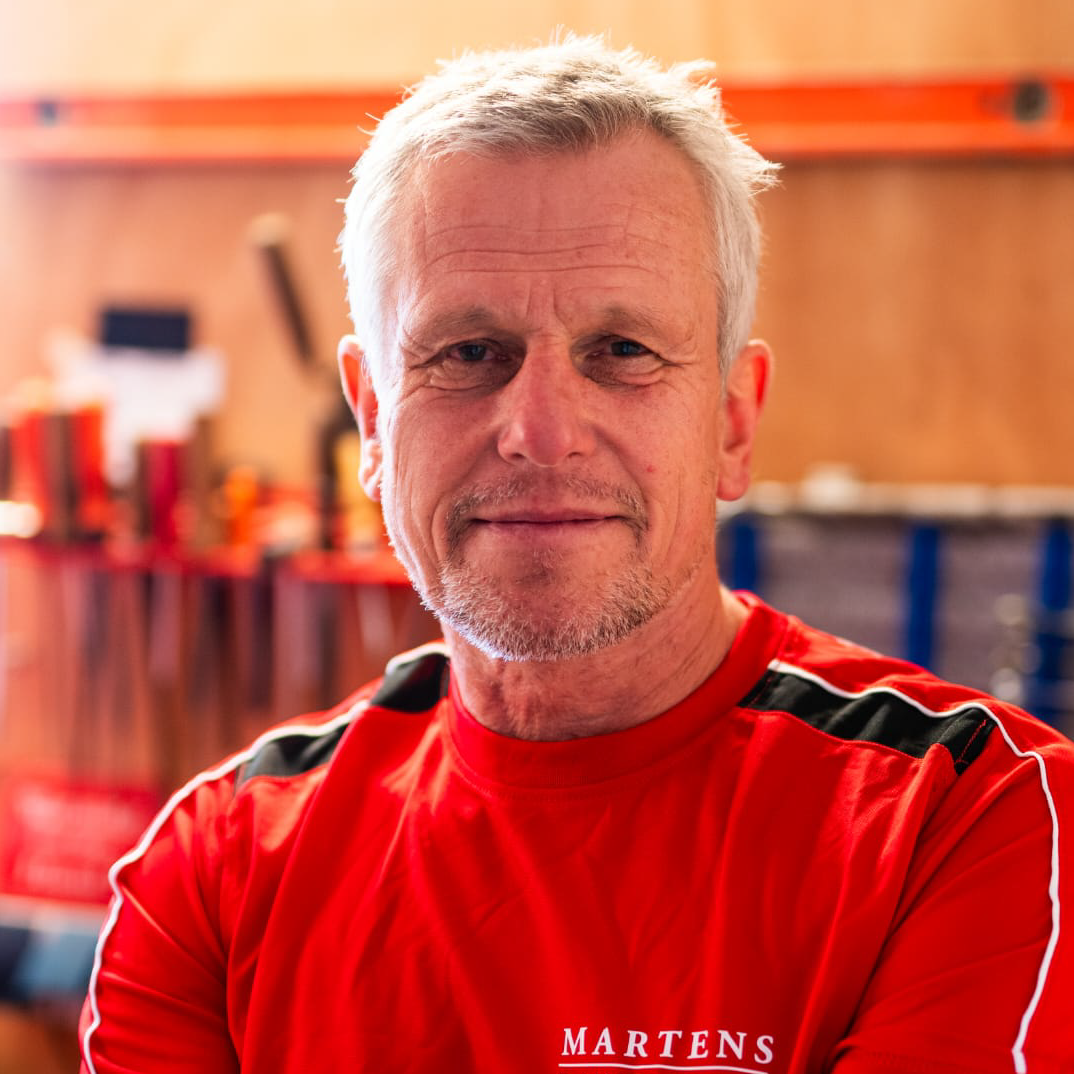 Ein Mann trägt ein rotes Hemd mit der Aufschrift „Martens“