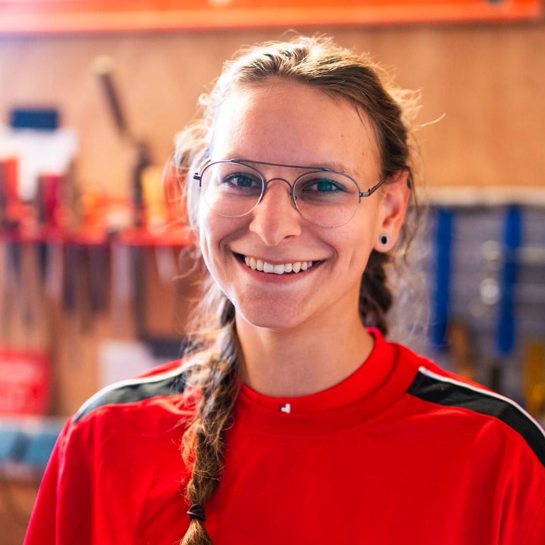 Eine Frau mit Brille und rotem Hemd lächelt in die Kamera.