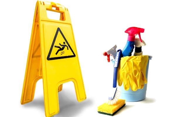 Panneau jaune « sol mouillé » à côté d'un seau bleu contenant des produits de nettoyage.