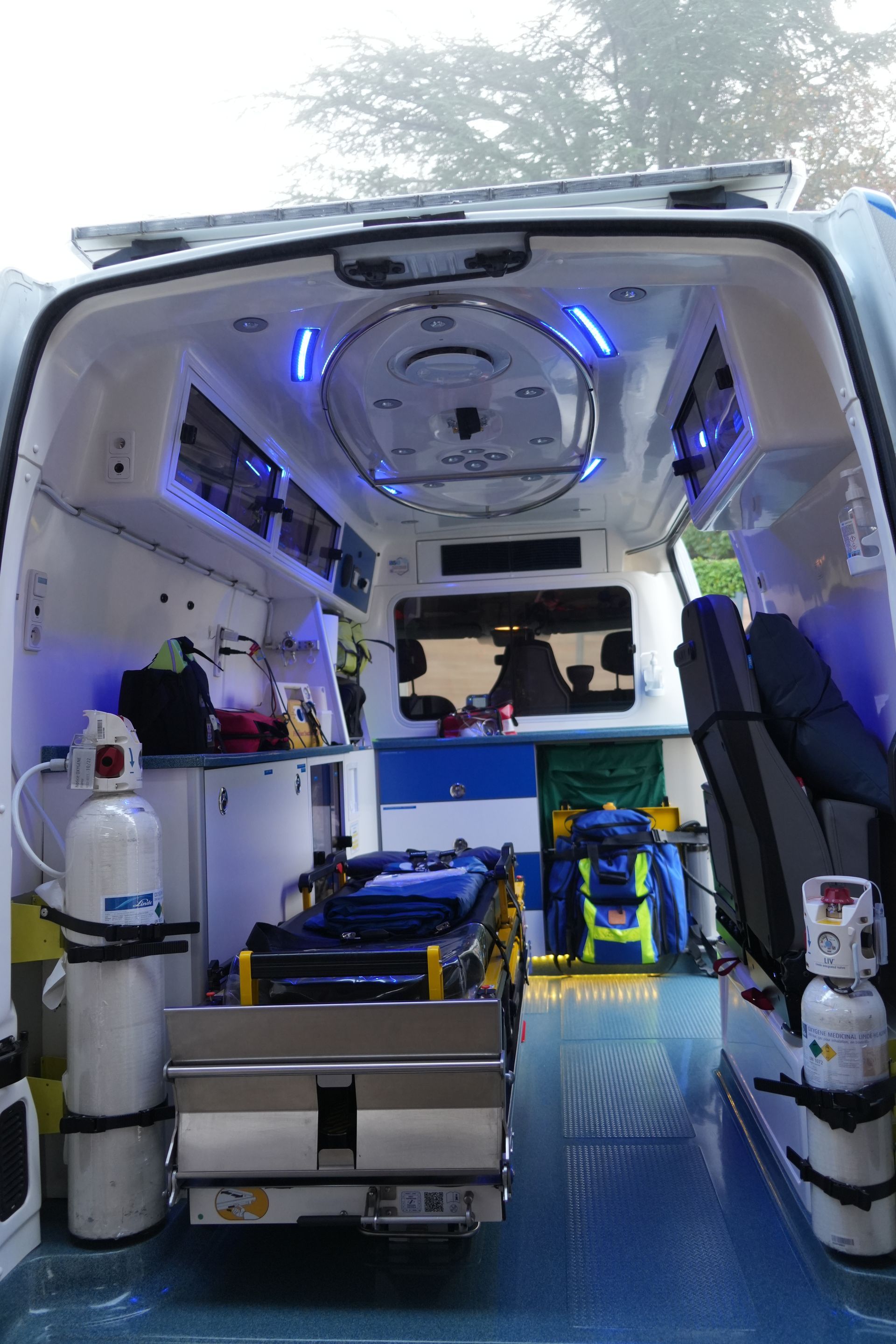 Intérieur d’une ambulance avec éclairage bleu, brancard et équipement médical