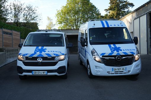 Deux fourgons Volkswagen blancs avec des marquages d’urgence bleus garés côte à côte à l’extérieur
