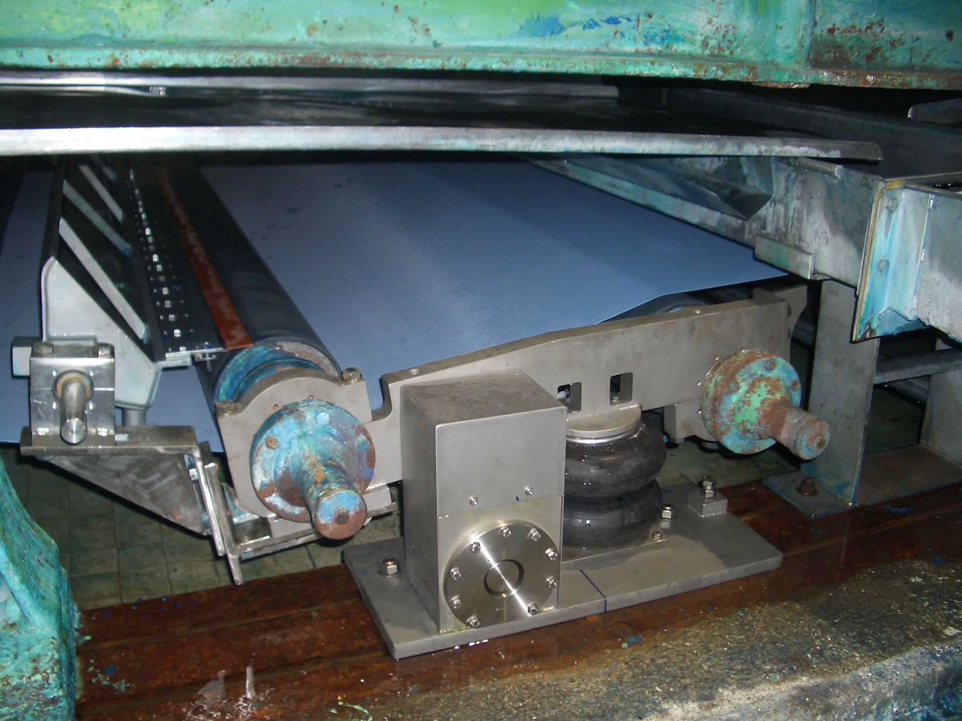 Una máquina con un cinturón azul está sentada sobre un piso de madera.