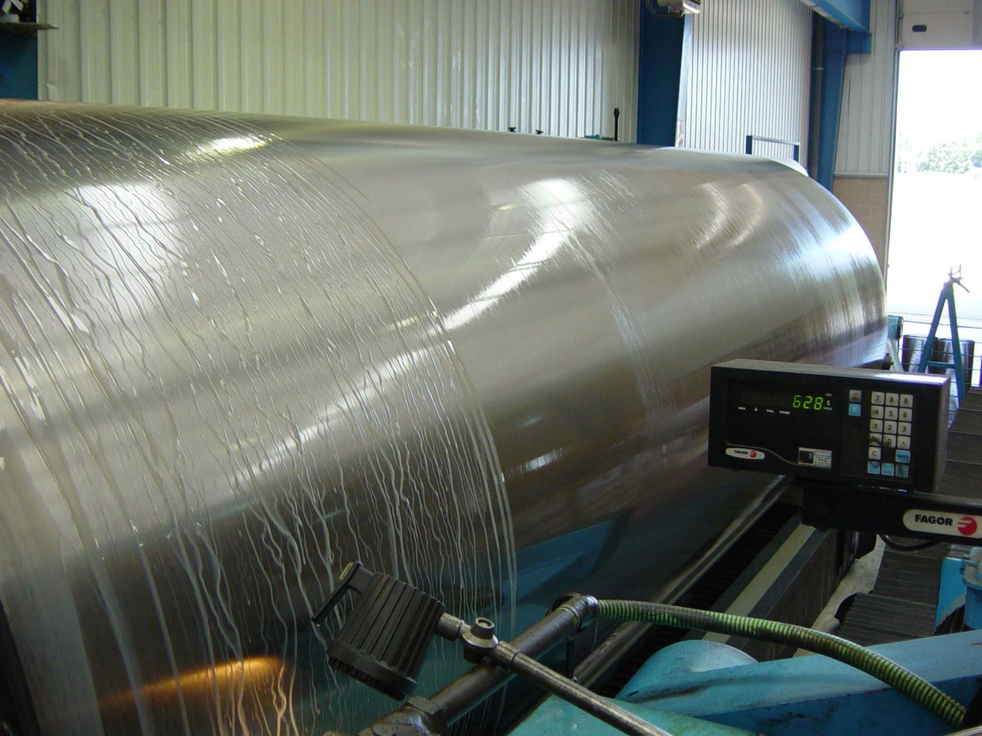 Un gran cilindro de acero inoxidable está siendo limpiado por una máquina.