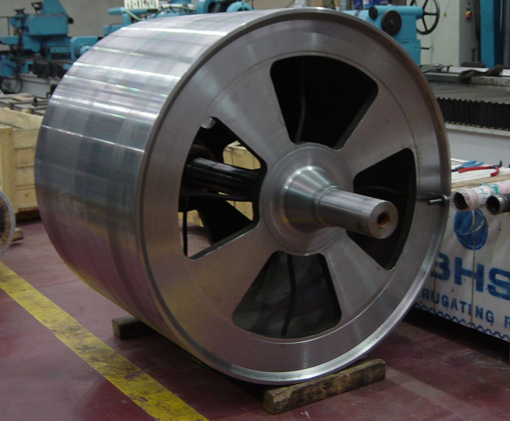 Una gran rueda de metal se encuentra frente a un cartel de BHS.