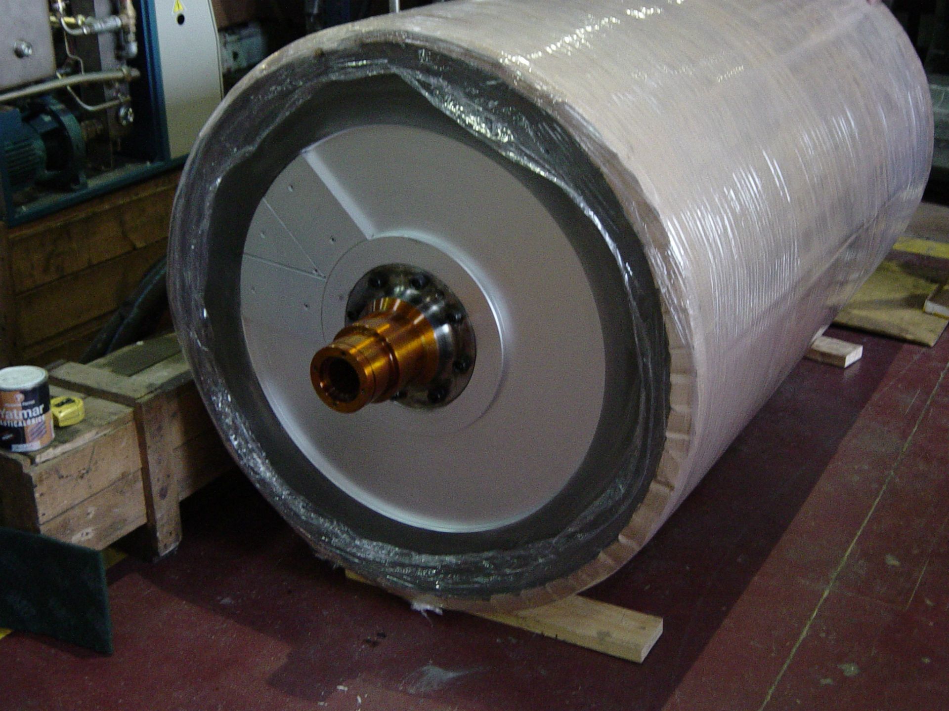 Un cilindro grande está envuelto en plástico y colocado sobre una paleta de madera.