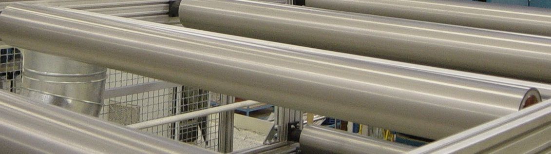 Un montón de tubos de metal están colocados uno encima del otro en una fábrica.