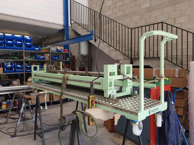 Un carrito verde está estacionado en un almacén al lado de una escalera.