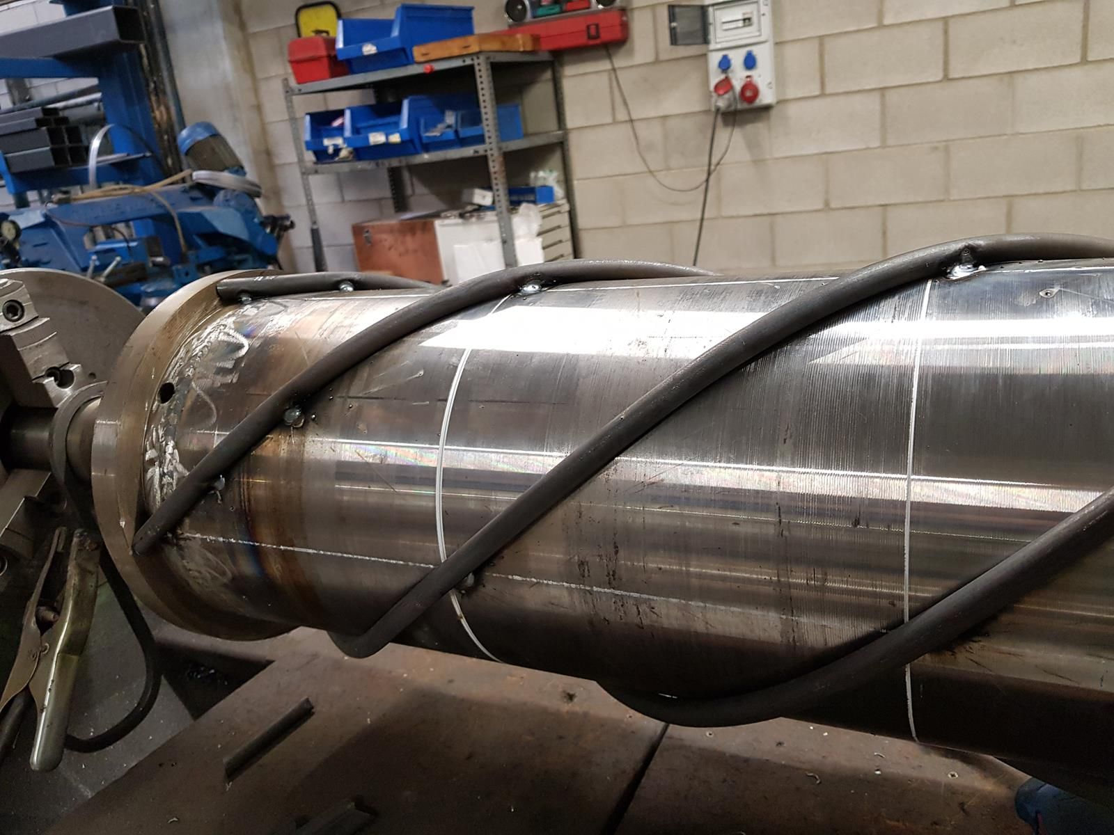 Una máquina está trabajando en un tubo de metal de gran tamaño en una fábrica.