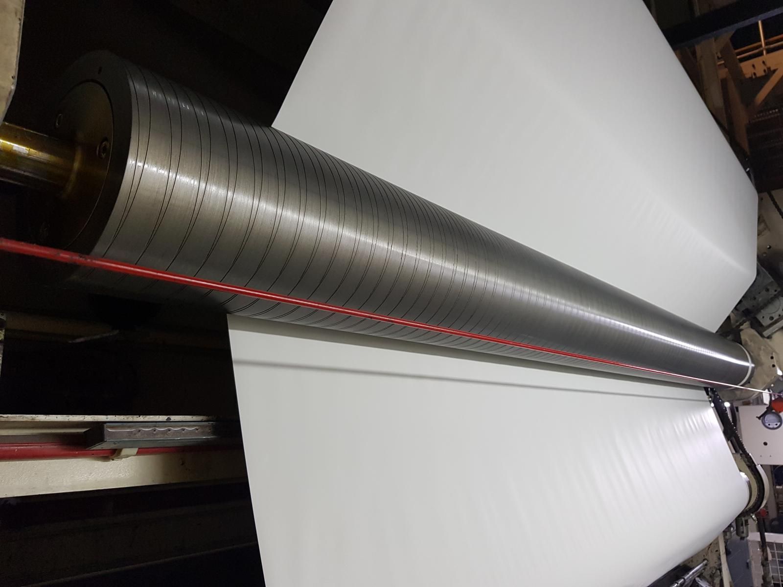 Un rollo grande de papel se está enrollando en una máquina.