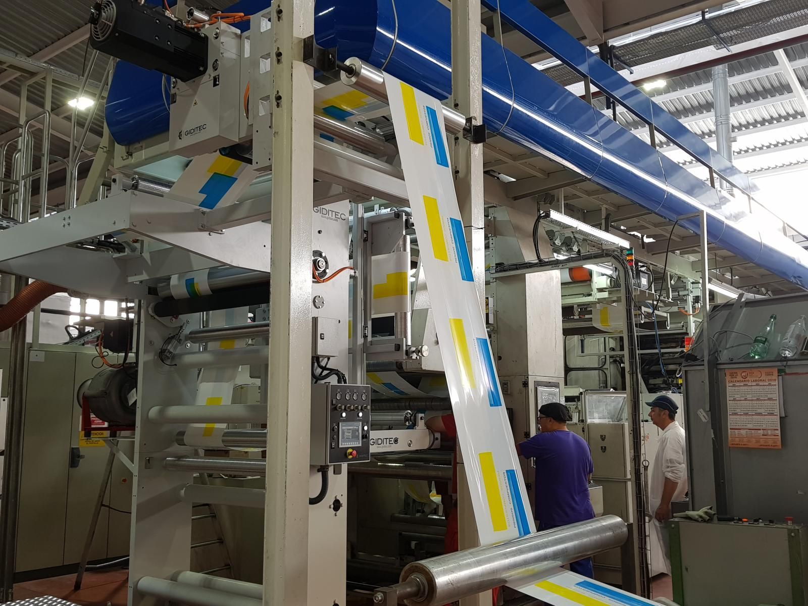 Un hombre está parado frente a una máquina en una fábrica.