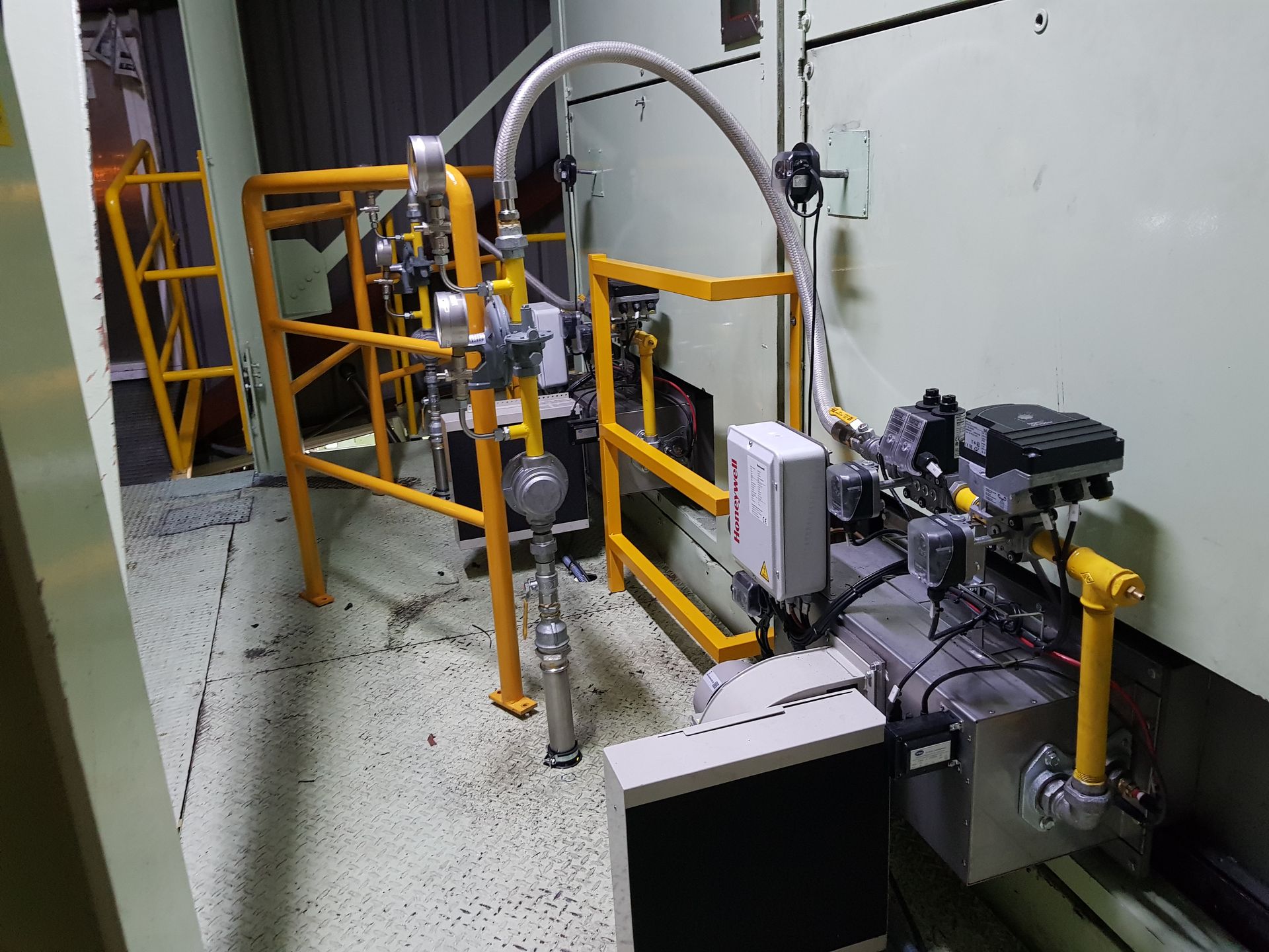 Una habitación con muchas tuberías y una valla amarilla.