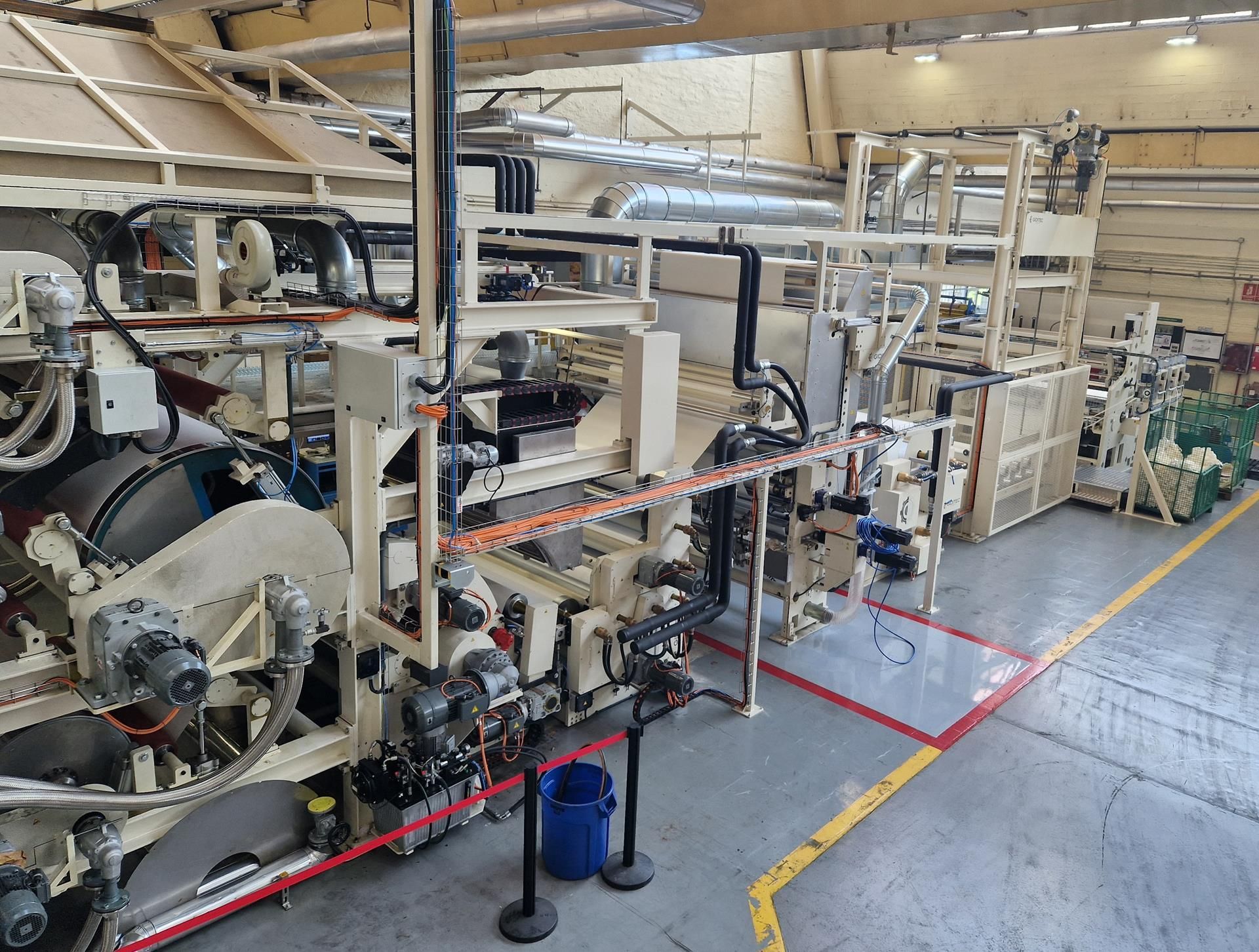 Una máquina grande se encuentra en una fábrica con una línea amarilla.