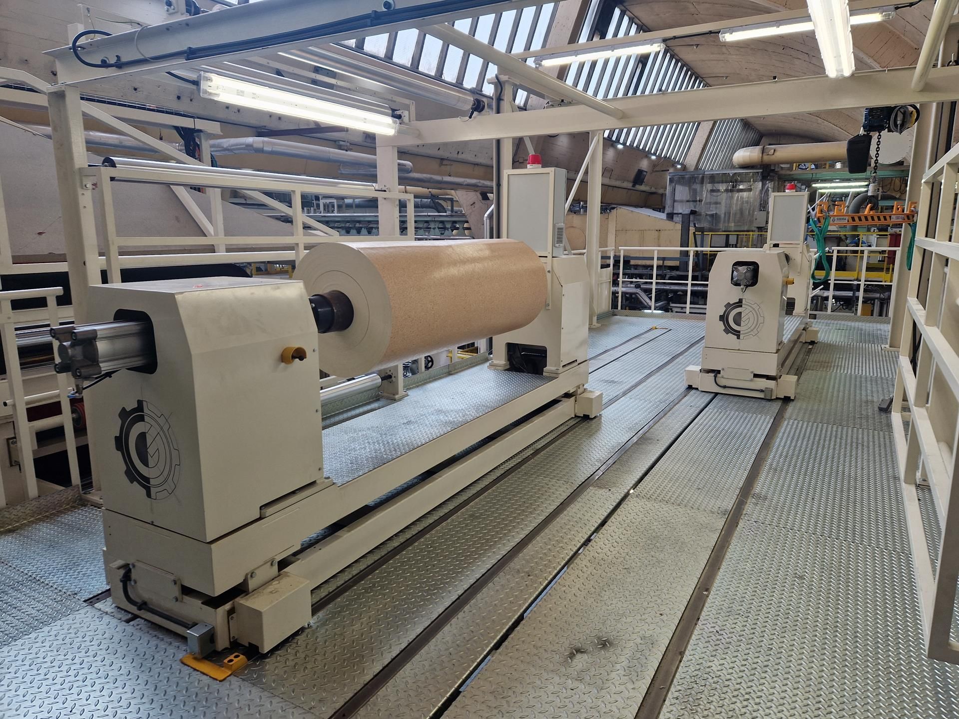 Un gran rollo de papel se encuentra encima de una máquina en una fábrica.