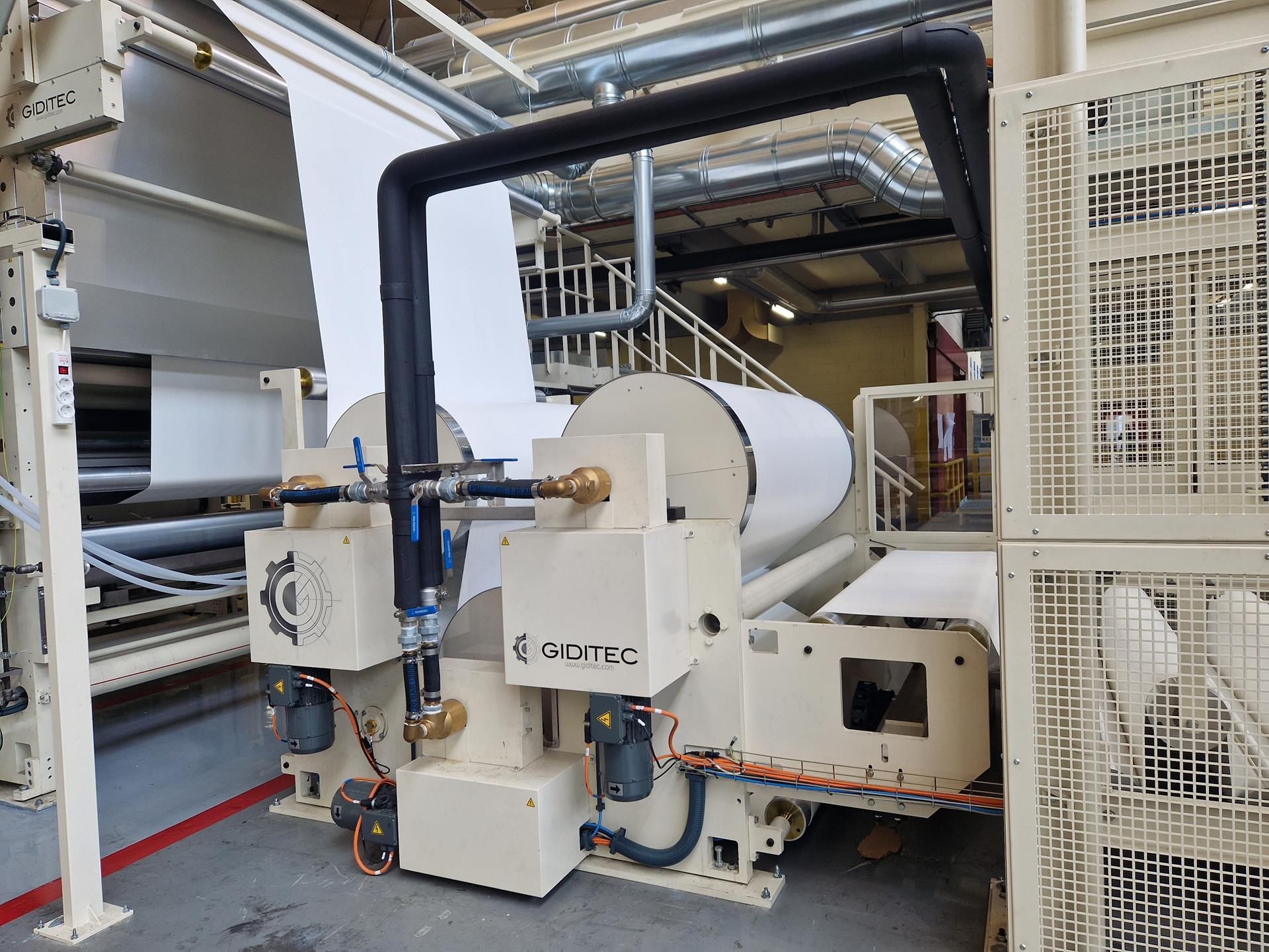 Una máquina en una fábrica con un gran rollo de papel sobre ella.