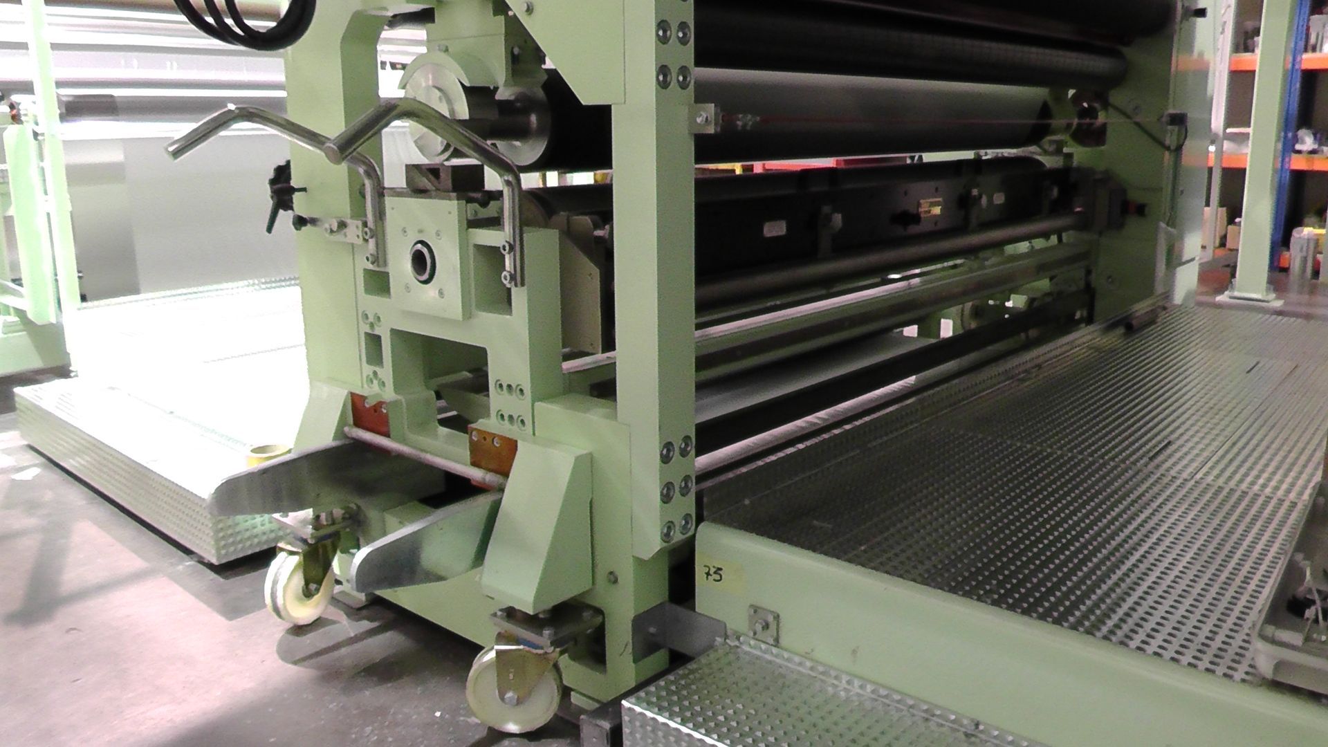 Una máquina verde está sentada sobre un piso de metal en un almacén.