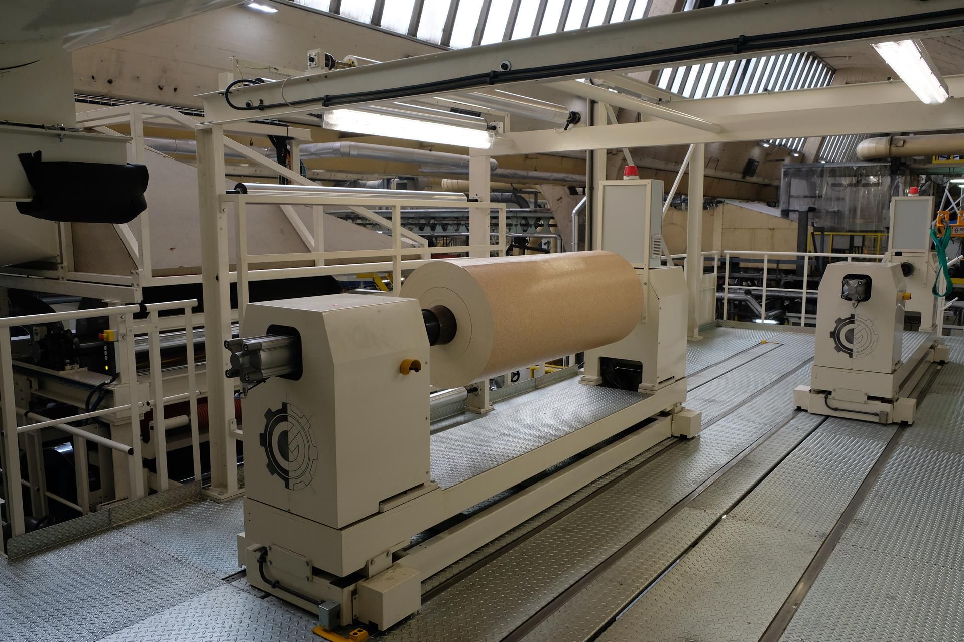 Un gran rollo de papel se encuentra en una máquina en una fábrica.