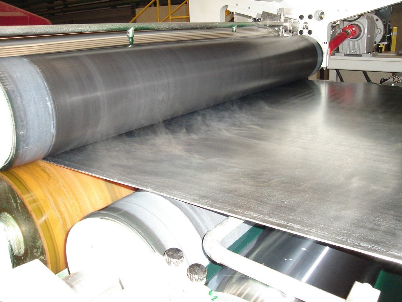 Una máquina está haciendo rodar una pieza de metal sobre una cinta transportadora.