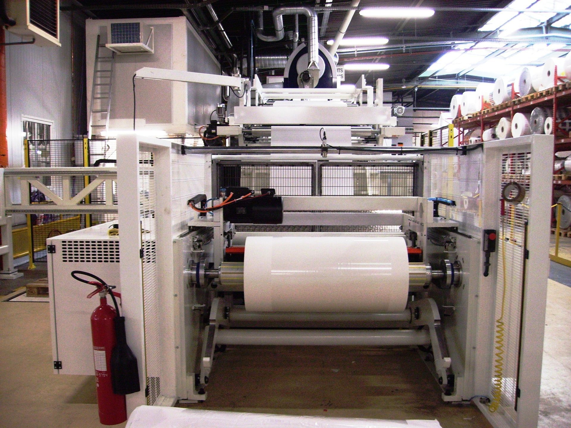 Un extintor de incendios está al lado de una máquina en una fábrica.