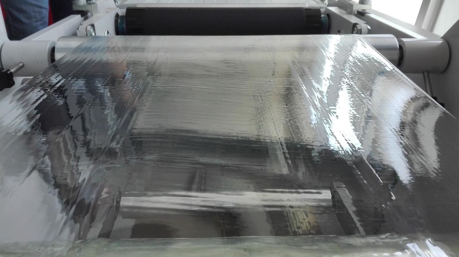 Un gran trozo de plástico transparente se enrolla en una cinta transportadora.