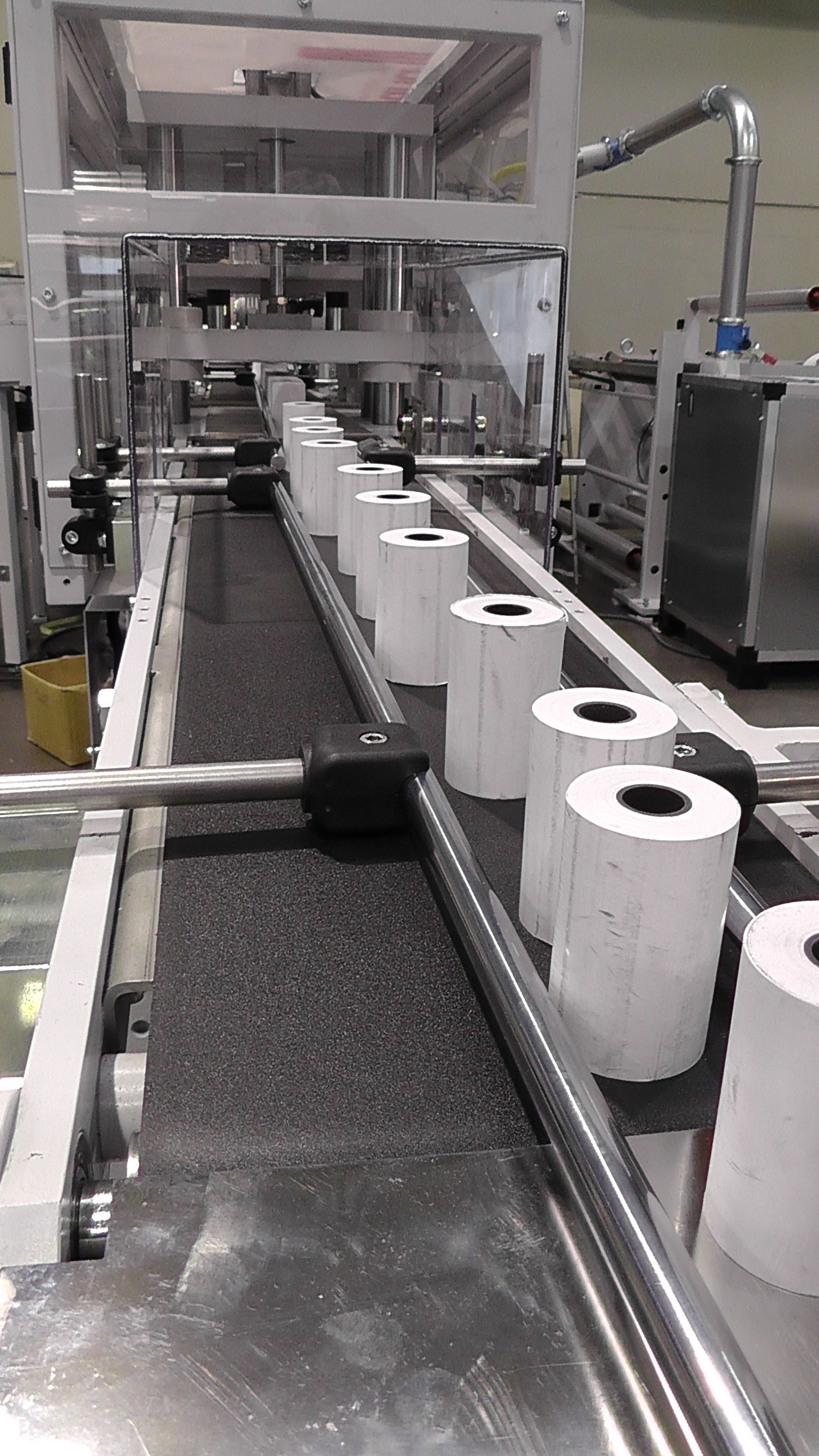 Una cinta transportadora llena de rollos de papel higiénico en una fábrica.